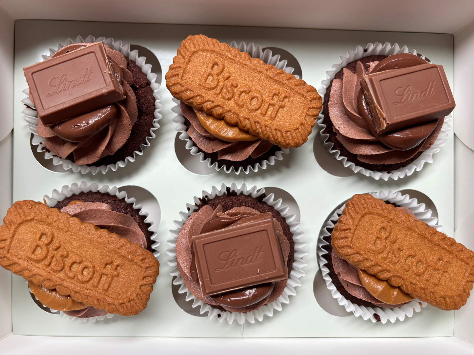 Box of chocolate cupcakes topped with Biscoff and Lindt chocolate squares