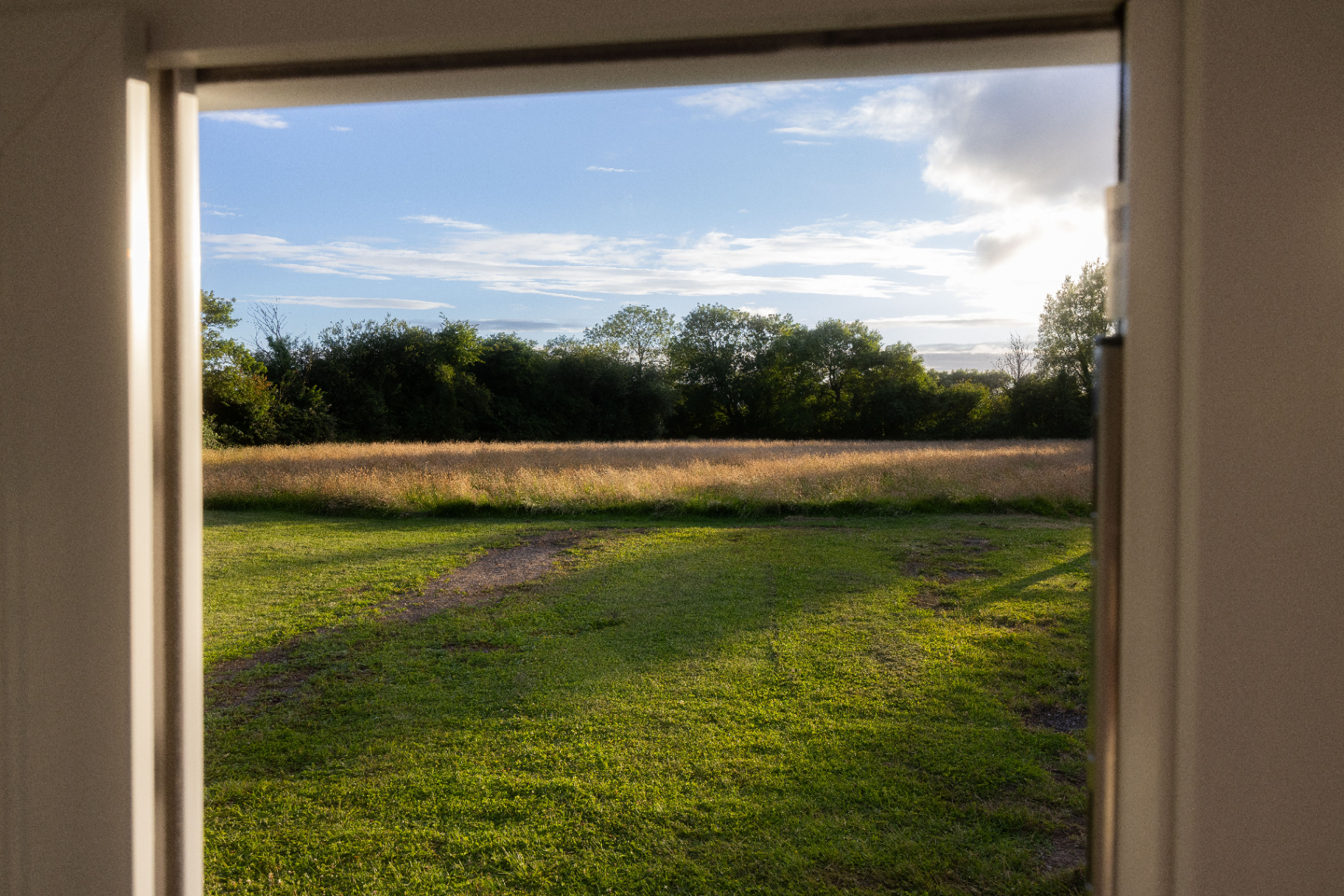View from the bakery doorway across the garden to Somerset fields at sunset