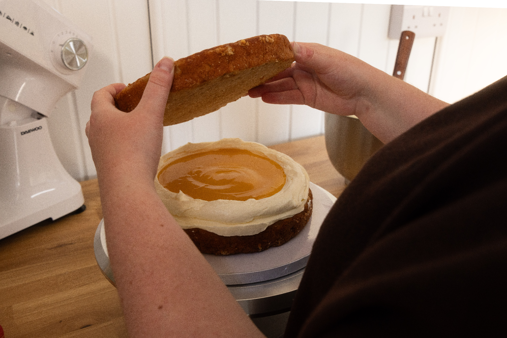 Placing the top sponge on a layered cake
